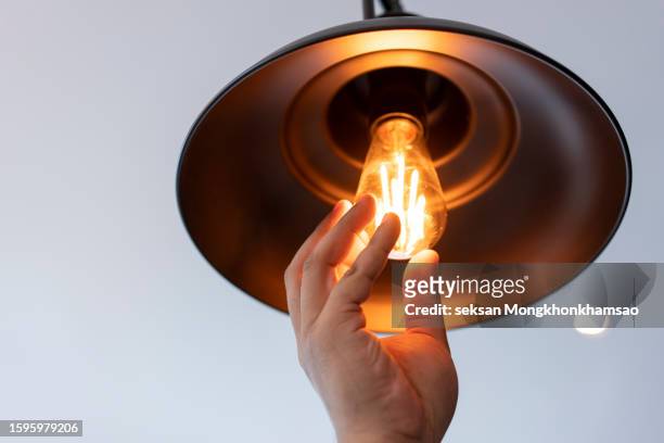 close up of lightbulb being screwed in - hände glühlampe stock-fotos und bilder