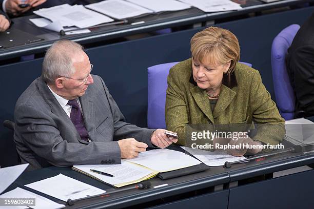 German Finance Minister Wolfgang Schaeuble shows German Chancellor Angela Merkel his phone screen during the Annual Economic Report 2013 of the...