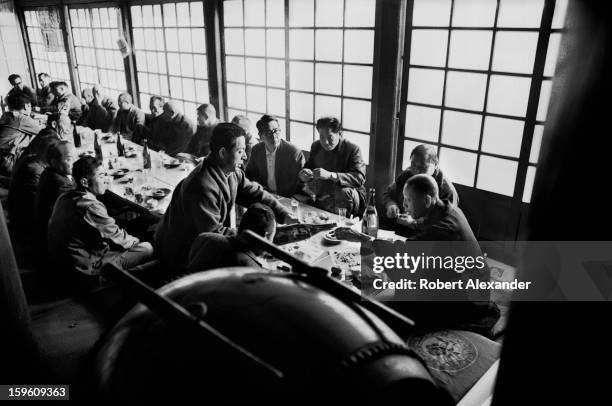 Community leaders meet to discuss civic affairs in the Buddhist temple in Noborito, Japan, near Tokyo. One man is pouring a cup of sake for the...