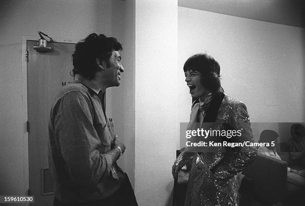 Mick Jagger of The Rolling Stones and musician Bill Graham are photographed sharing a laugh backstage in 1972 in Long Beach, California. CREDIT MUST...