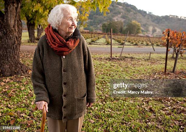 senior woman walking outdoors with a cane. - walking stick photos et images de collection