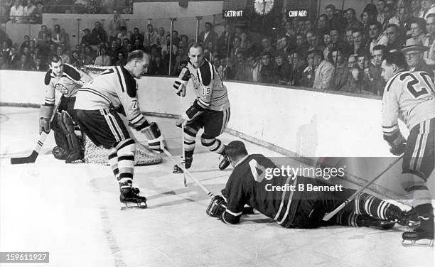 Red Kelly of the Toronto Maple Leafs tries to cover the puck as Cliff Pennington, Doug Mohns and Leo Boivin of the Boston Bruins surround him as...