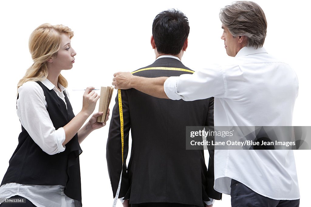 Fashion designer taking a measurement of  businessman