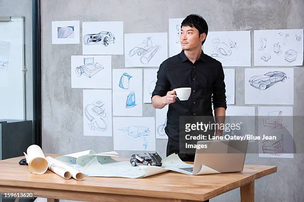 car designer with a cup of coffee in studio - auto ontwerper stockfoto's en -beelden
