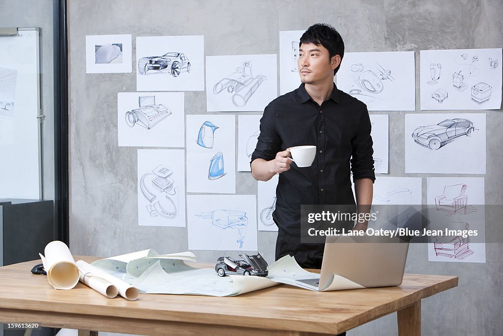 Car designer with a cup of coffee in studio