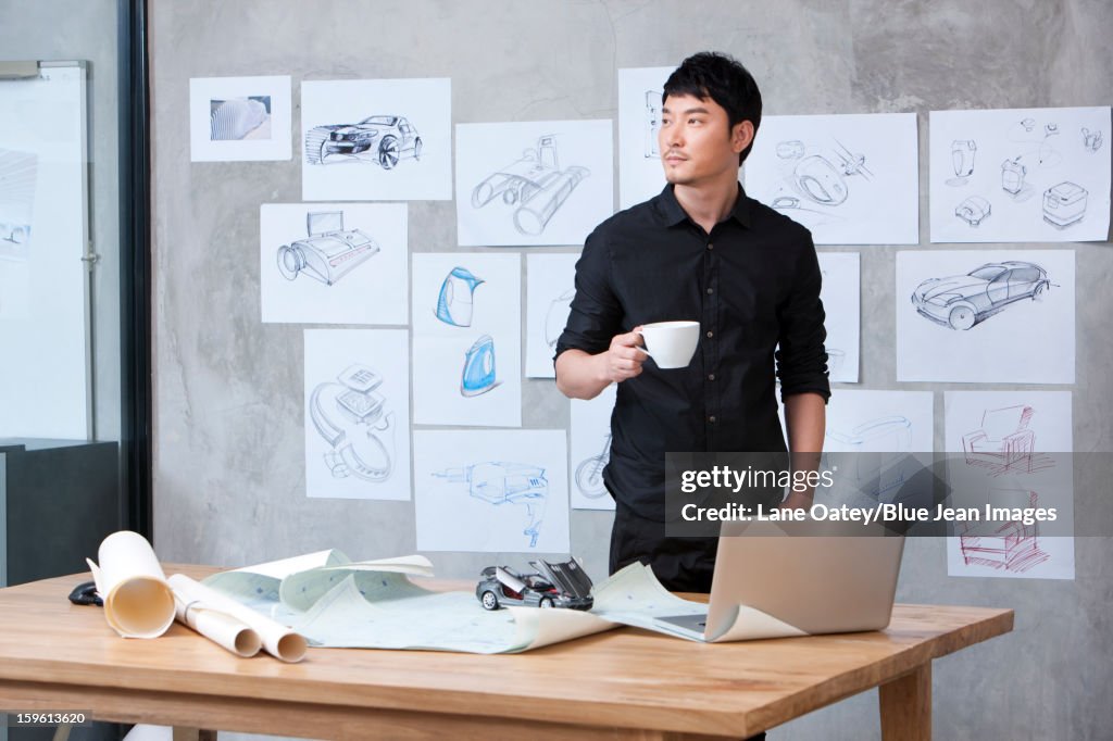 Car designer with a cup of coffee in studio