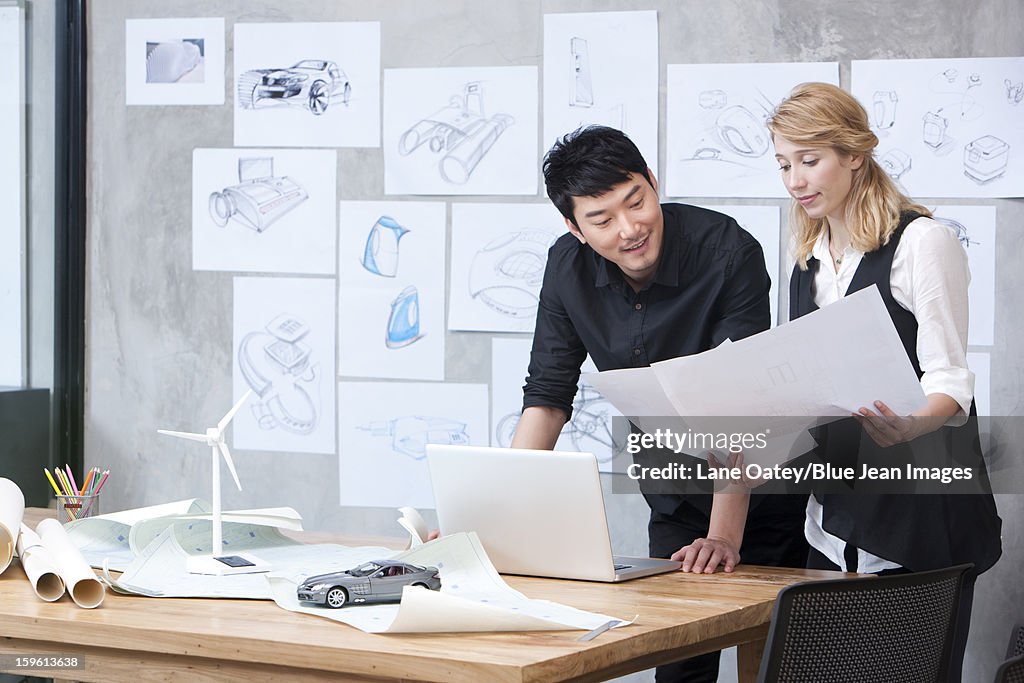 Designers studying blueprint in studio