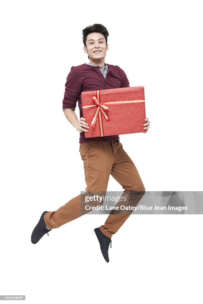 Cheerful young man with gift in Chinese New Year