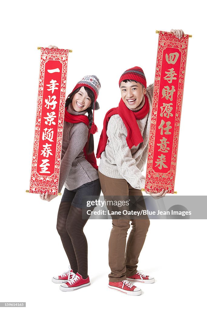 Cute young couple celebrating Chinese New Year with couplets