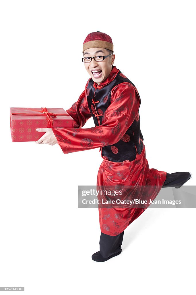 Happy young man in Tang suit holding gift box