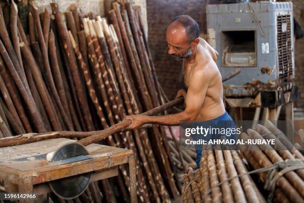 An Iraqi carpenter works in front of an air-conditioner in a workshop in Hamada market in central Baghdad during a heatwave on August 13, 2023.