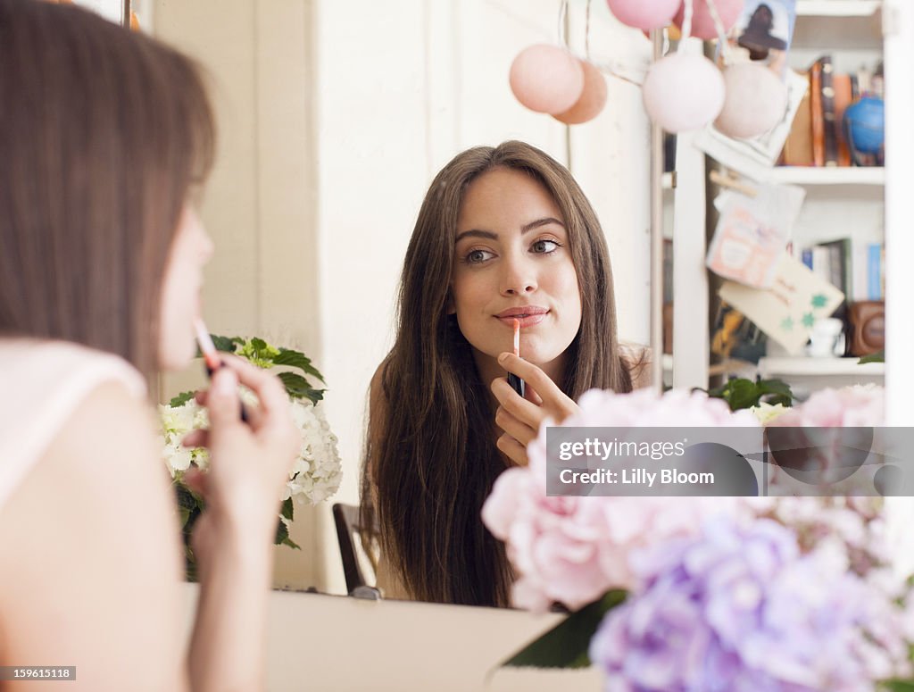 Woman applying make up in mirror