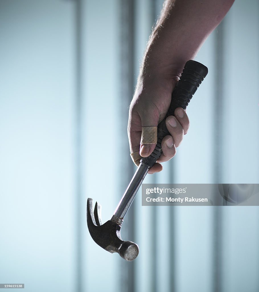 Man holding claw hammer with adhesive plaster on thumb