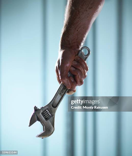 man holding adjustable spanner with oil dripping - adjustable wrench stock-fotos und bilder