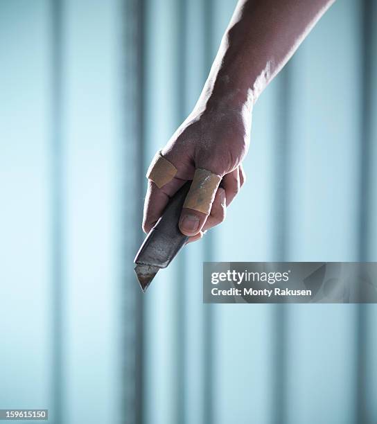 man with adhesive plasters on thumb and finger holding utility knife - cutter stock-fotos und bilder