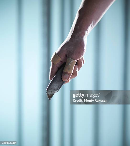 man with adhesive plasters on thumb and finger holding utility knife - craft knife stock pictures, royalty-free photos & images