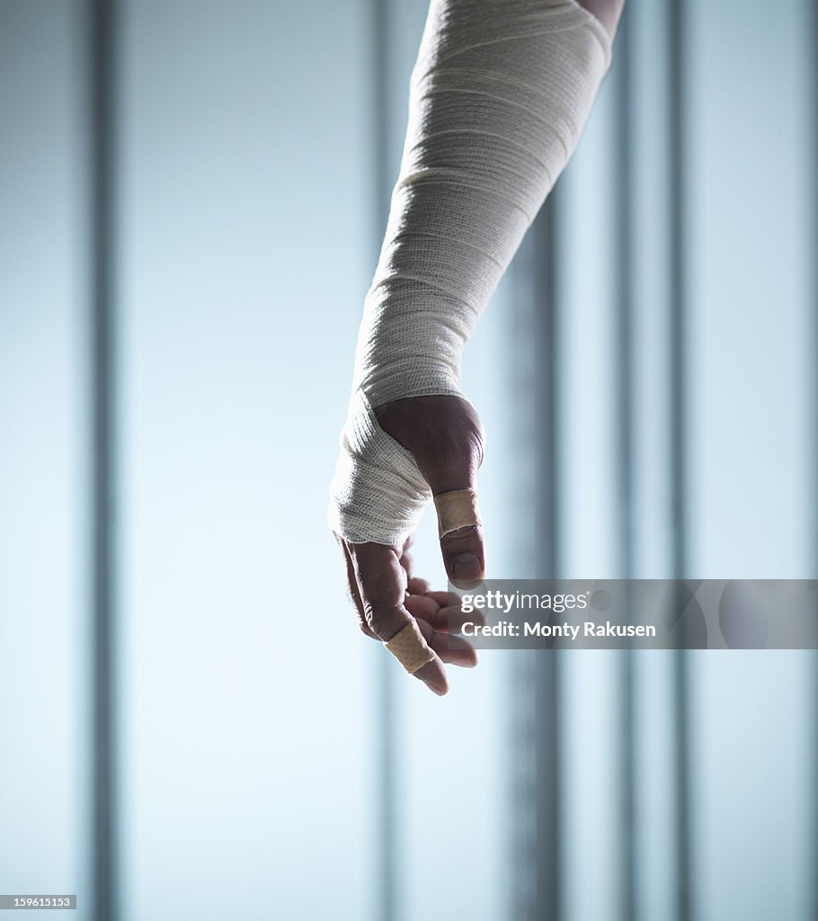 Man with medical bandage wrapped around arm and hand with adhesive plasters on finger and thumb