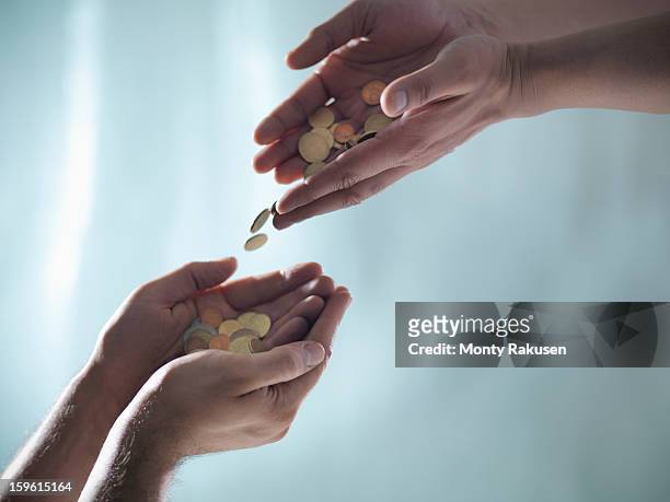 man pouring euro coins into another man's cupped hands - offering ストックフォトと画像