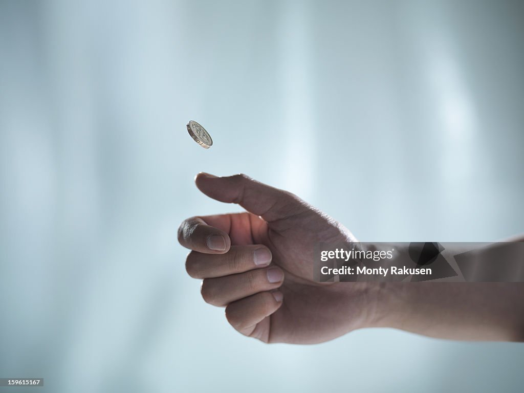 Man flipping one pound coin, pounds sterling