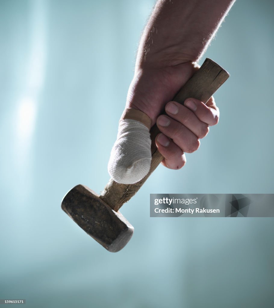 Man with bandaged thumb holding hammer