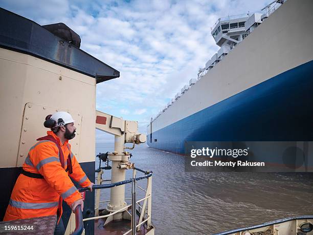 tug worker wearing hard hat looking at ship - crew stockfoto's en -beelden