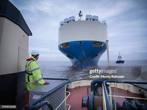 tug worker on deck of tug looking at ship out to sea - tug boat stock-fotos und bilder