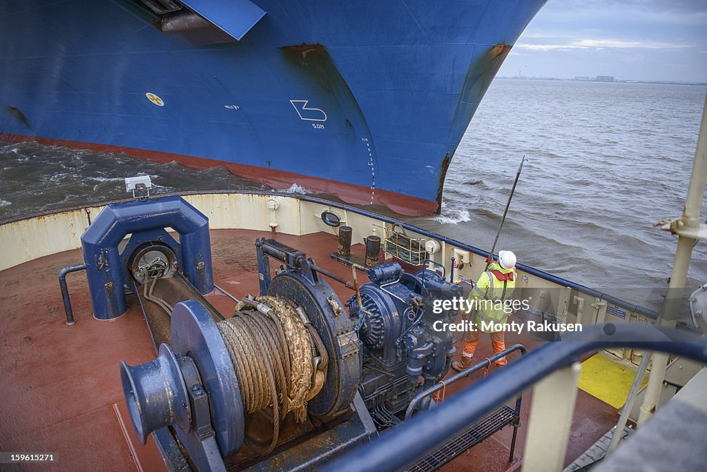 Tug worker catching rope on tug's deck, high angle