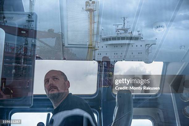 tug captain looking into distance, with reflections of ship on glass - ship's bridge stock pictures, royalty-free photos & images