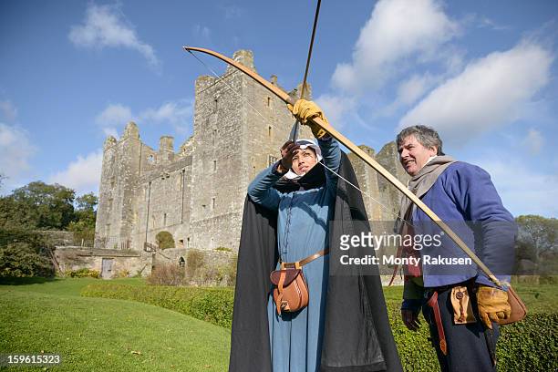 man teaching history student archery in period dress outside bolton castle, a 14th century grade 1 listed building, scheduled ancient monument - bow arrow stock-fotos und bilder