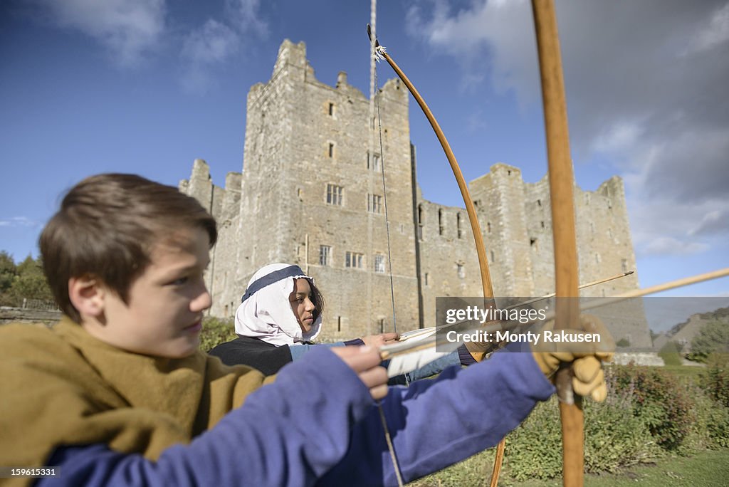 History students in period dress practising archery outside Bolton Castle, a 14th century Grade 1 listed building, Scheduled Ancient Monument