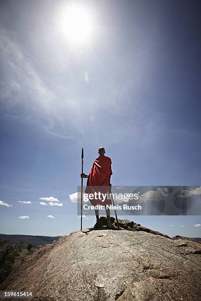 maasai man standing on top of rock - rift valley stock pictures, royalty-free photos & images