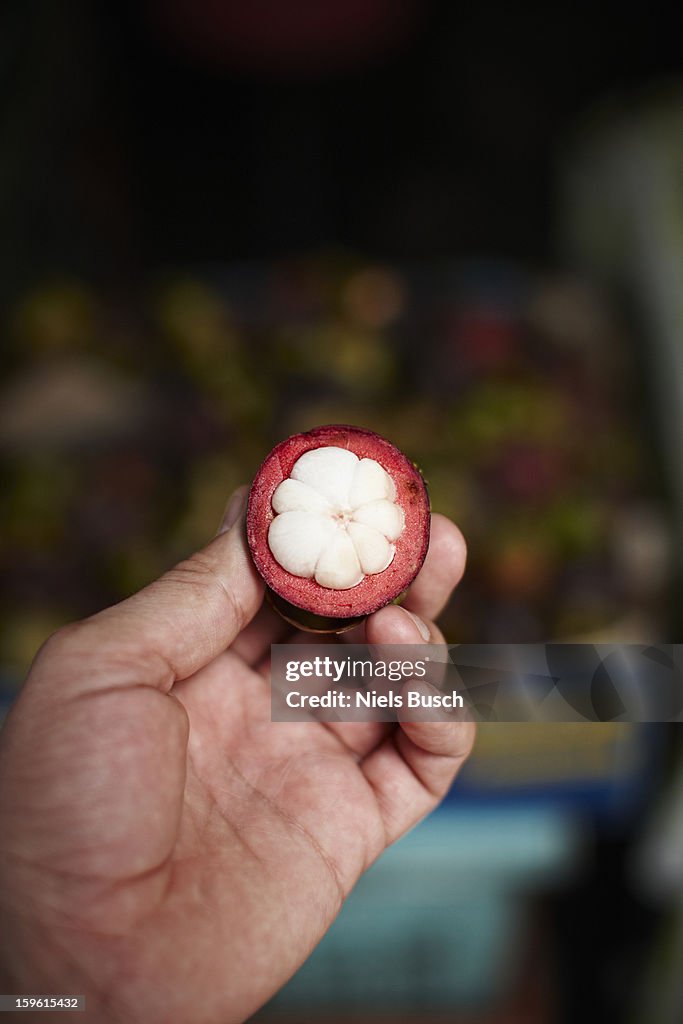 Hand holding piece of mangosteen fruit