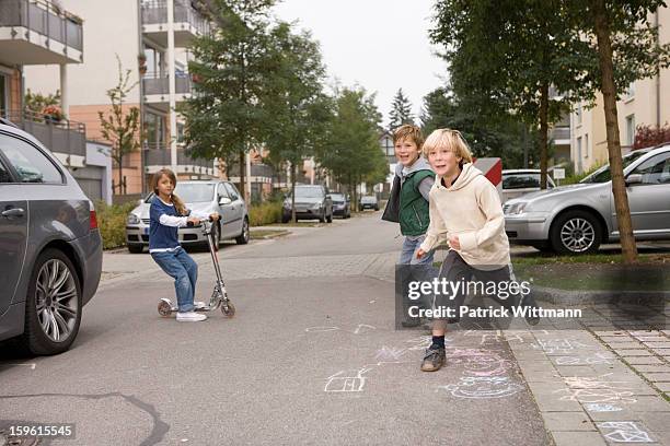 children playing on suburban street - nachbarschaft stock-fotos und bilder