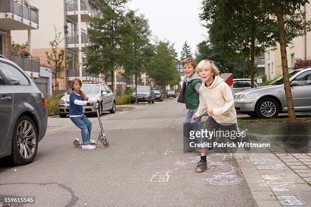 children playing on suburban street - carro de corrida fotografías e imágenes de stock