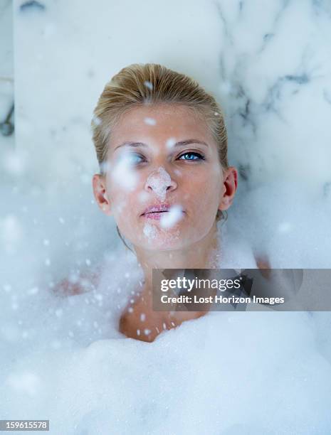 woman playing in bubble bath - woman bath bubbles stock-fotos und bilder