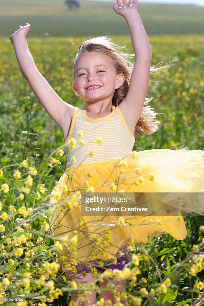 Smiling girl playing in field of flowers