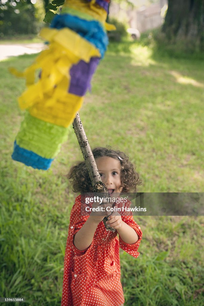 Girl swinging at pinata at party