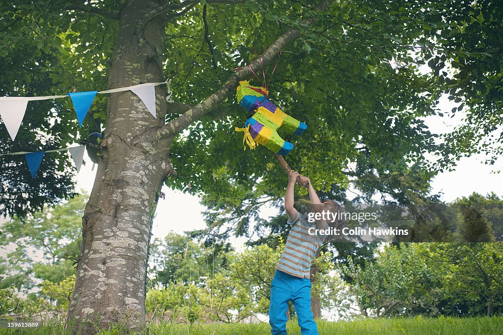 Boy swinging at pinata at party