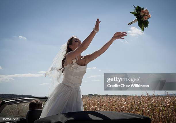 newlywed bride tossing bouquet from car - bruid stockfoto's en -beelden