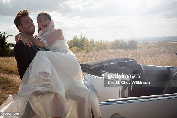 newlywed groom carrying bride outdoors - wedding couple laughing photos et images de collection