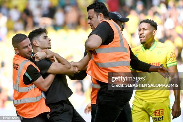 Security guards restrain a man who ran onto the pitch at the end of the French L1 football match between FC Nantes and Toulouse FC at the Stade de la...