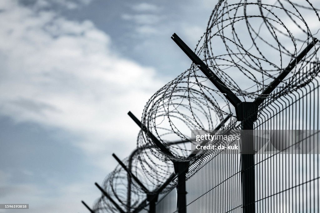 Stacheldrahtzaun. Gefängnis oder Grenzzaun mit Stacheldraht gegen dunklen Himmel. Sicherheitskonzept