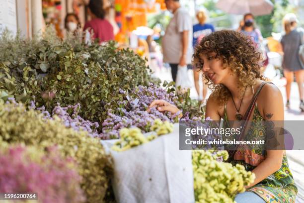 tourist mesmerized by market stall flowers during vacation. - flower stall stock pictures, royalty-free photos & images