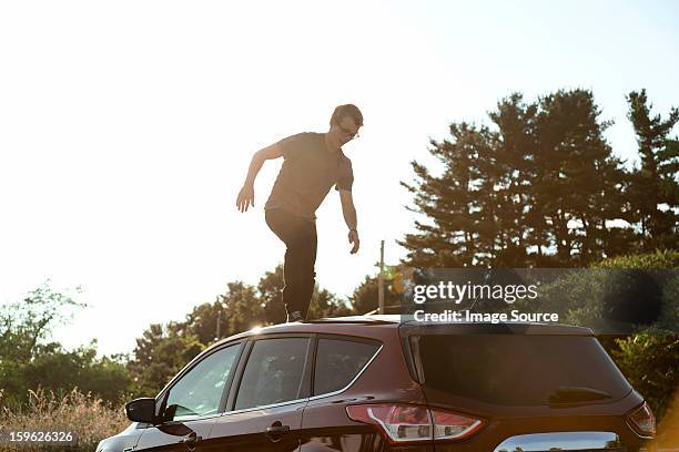 young man walking across car roof - car roof stock pictures, royalty-free photos & images