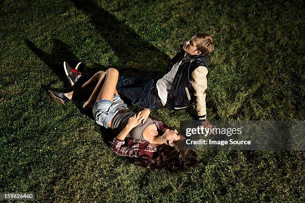 couple lying on grass at night, high angle - mann lässig gras sitzen stock-fotos und bilder