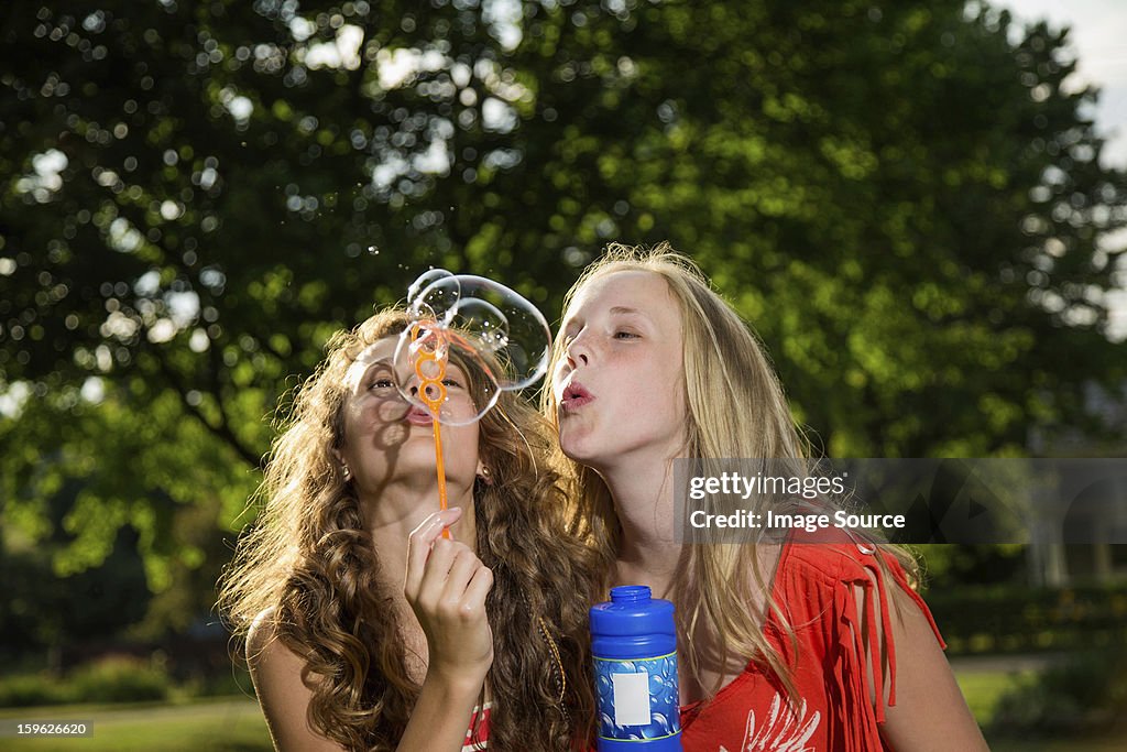 Two girls blowing bubbles with bubble wand