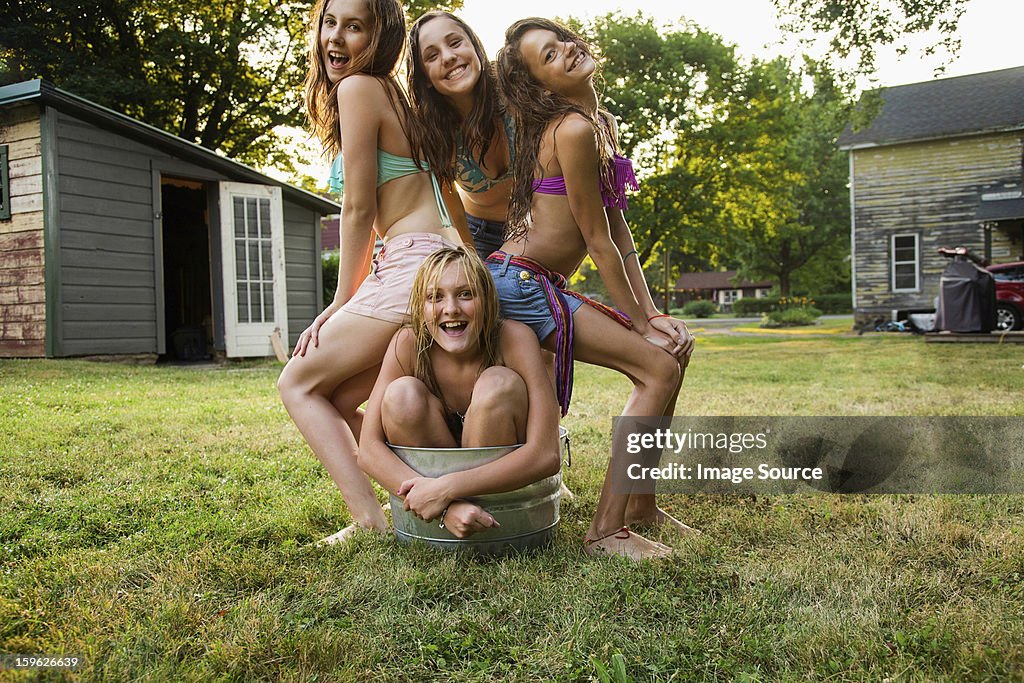 Girl crouching in bucket with friends sitting on her