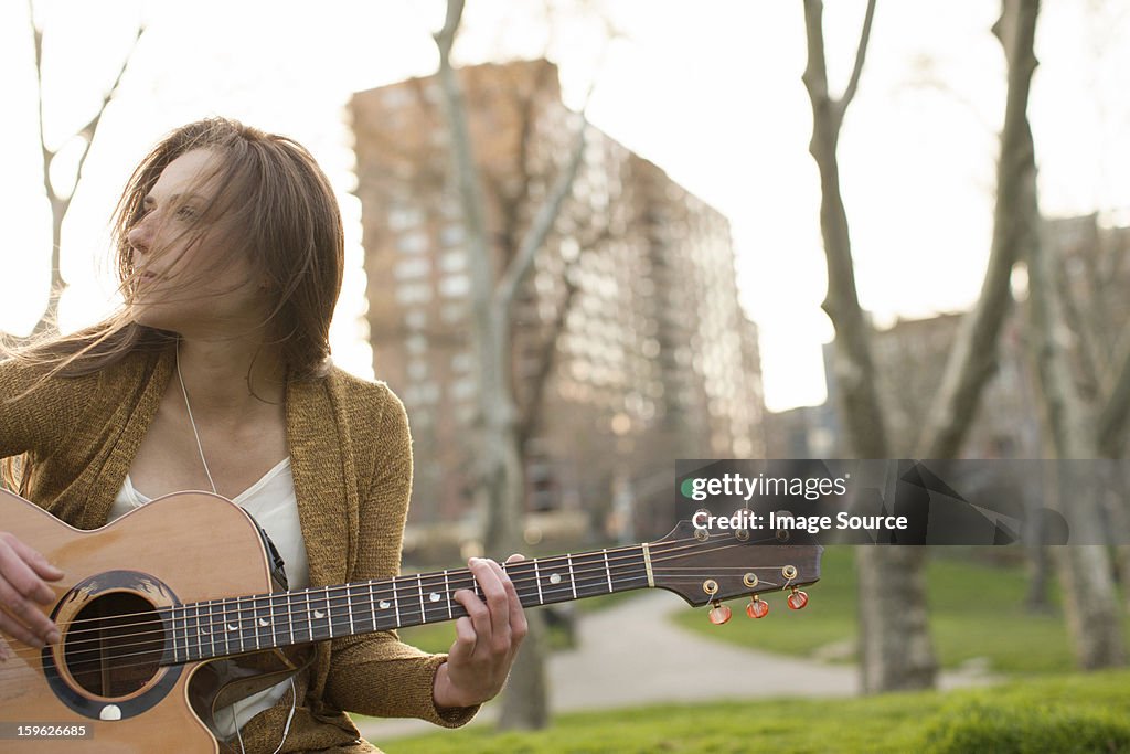 Young woman playing guitar outdoors