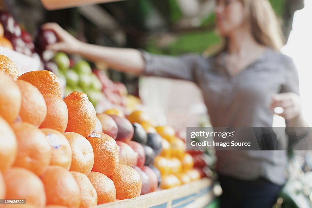 Young woman picking out fruit from stall