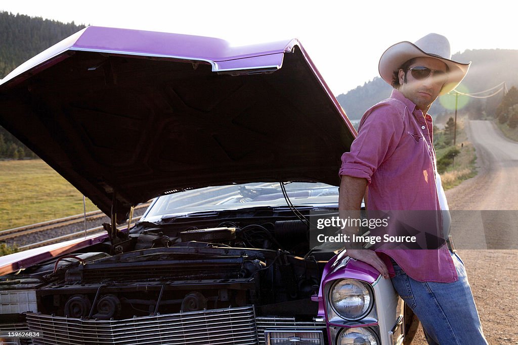 Man leaning against vintage car with hood up